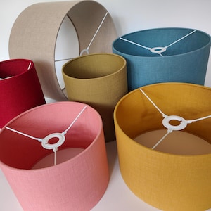 Peut inclure: Six abat-jours de différentes couleurs en tissu texturé. Les abat-jours sont tous cylindriques et ont un anneau métallique blanc en haut.