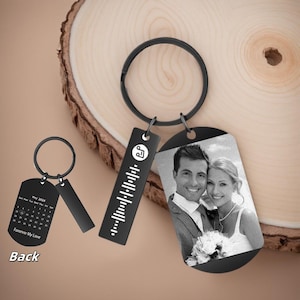 May include: Black metal keychains with a circular ring. One keychain features a photo of a couple, another has a Spotify code, and the third has a calendar with the text "Forever My Love" and "Back".