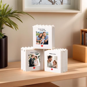 May include: Three white block photo frames, each displaying a different family photo. The top frame has a family of three with the text "Love you always, no matter what." The other frames show a wedding and a father and son. Each frame has a red heart.