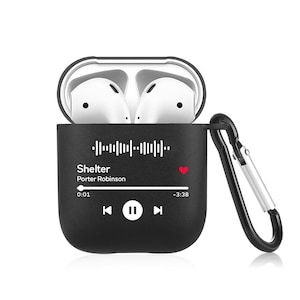 May include: Black Airpods case with a black and white graphic of a music player with the song "Shelter" by Porter Robinson playing. The case has a carabiner clip.