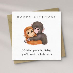May include: A birthday card with a brown envelope. The card shows two cartoon monkeys embracing. The text "HAPPY BIRTHDAY" is at the top, and the message "Wishing you a birthday you'll want to hold onto" is at the bottom.