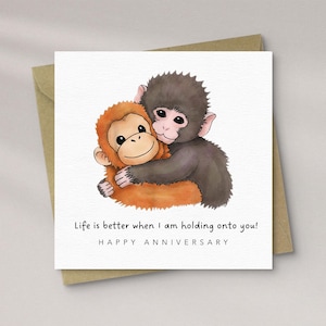 May include: A square greeting card featuring a watercolour illustration of two monkeys embracing. One is orange, the other grey. Text reads "Life is better when I am holding onto you!" and "HAPPY ANNIVERSARY".