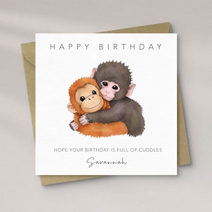 May include: A square birthday card with a brown envelope. The card features a watercolour illustration of two hugging monkeys. The text reads "HAPPY BIRTHDAY", "HOPE YOUR BIRTHDAY IS FULL OF CUDDLES", and "Savannah".