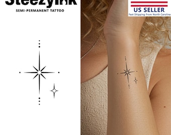 May include: A black and white temporary tattoo design of a star with smaller stars on either side. The tattoo is shown on a person's wrist.