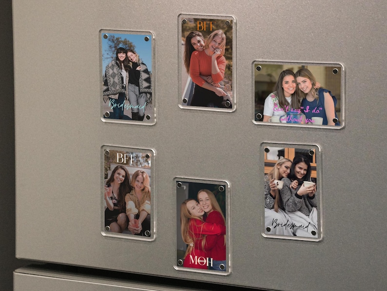 May include: Rectangular clear acrylic magnets with photos of people, attached to a silver refrigerator. Some magnets have the word "BFF" or "Bridesmaid" in script. The photos show groups of women in various settings, hugging and smiling.