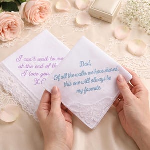May include: Two white fabric handkerchiefs with lace trim. One features blue embroidery reading: Dad, Of all the walks we have shared, this one will always be my favorite. The other has purple embroidery reading: I can't wait to meet you at the end of the aisle. I love you, XOXO.
