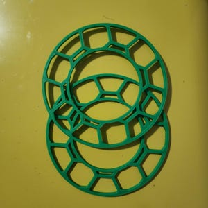 May include: Two green plastic rings with a honeycomb pattern. The rings are stacked on top of each other.