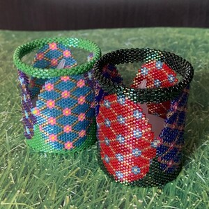 May include: Two beaded candle holders, one with a blue and pink floral pattern and the other with a red and blue floral pattern.