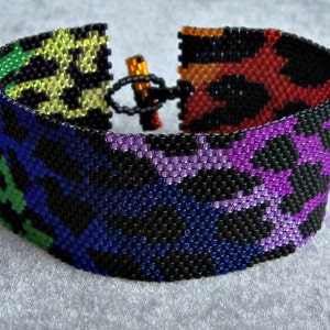 May include: A colorful beaded bracelet with a black background and a variety of colors including green, yellow, orange, red, purple, and blue.