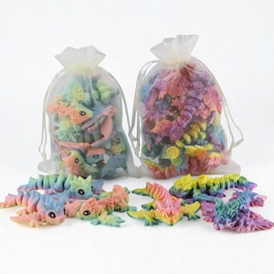 May include: Two organza bags filled with miniature fantasy creatures and flowers in pastel shades. The creatures and flowers are in pink, blue, yellow, and green. Some of the creatures are outside of the bags.