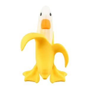 May include: A whimsical, yellow banana-shaped object with a white duck head emerging from the top. The duck has a bright orange beak and black eyes. The banana peel is peeled back, revealing the duck's head.