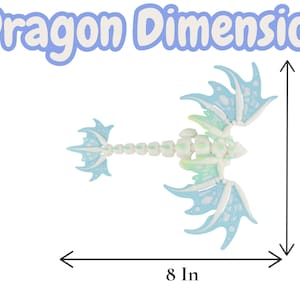May include: A light blue and white dragon toy with a skeletal design, wings, and tail. The dragon measures 8 inches wide and 7.5 inches tall. The text "Dragon Dimensions" is at the top.