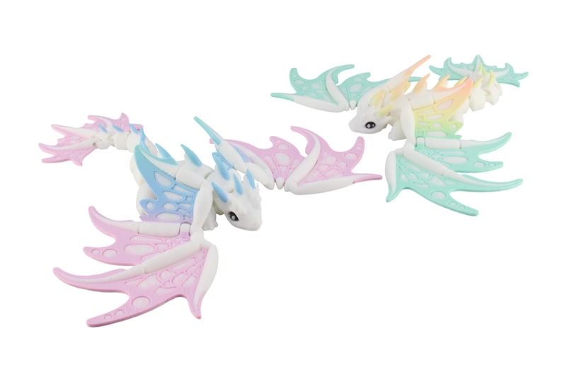 May include: Two articulated dragon toys in pastel colors. One dragon features pink and blue wings, while the other has mint green and yellow wings. The dragons have white bodies and small black eyes, with a fantasy theme.
