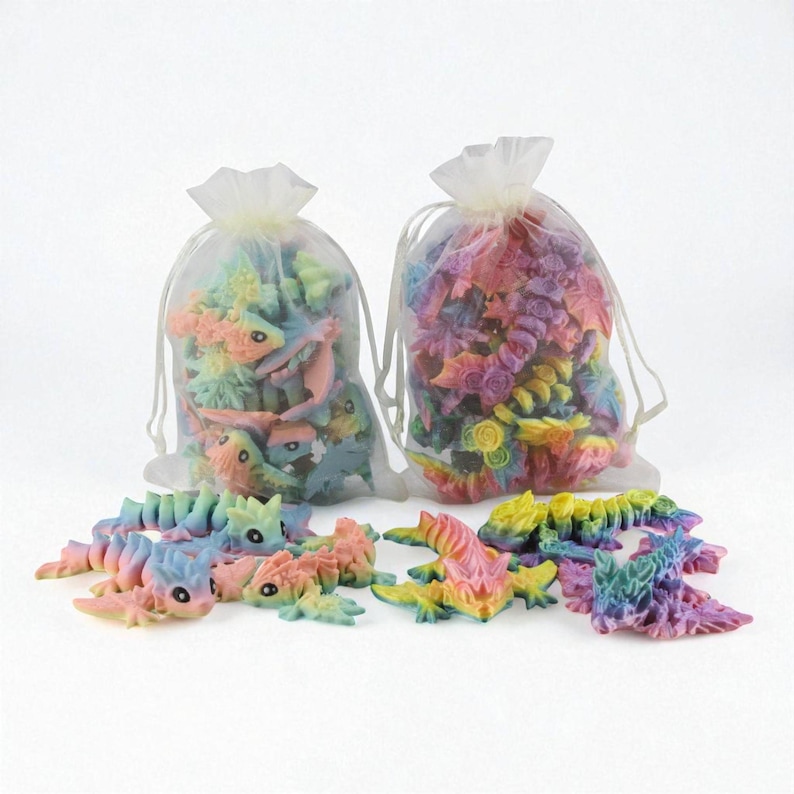 May include: Two organza bags filled with miniature fantasy creatures and flowers in pastel shades. The creatures and flowers are in pink, blue, yellow, and green. Some of the creatures are outside of the bags.