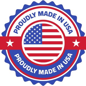 May include: A circular emblem with a blue scalloped border, red and white inner rings, and a central American flag design. The words "PROUDLY MADE IN USA" are written in white text around the emblem, with two red banners featuring white stars.