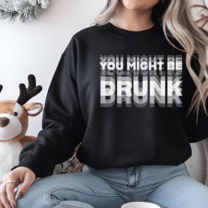 Puede incluir: Sudadera negra con texto blanco que dice "You Might Be Drunk" en un estilo de fuente superpuesto.