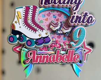 May include: A multi-layered cake topper featuring a white roller skate with pink laces and a yellow lightning bolt. The text reads Rolling into 9 Annabelle. The design includes a circular shaker element filled with pink and white sprinkles and hearts.