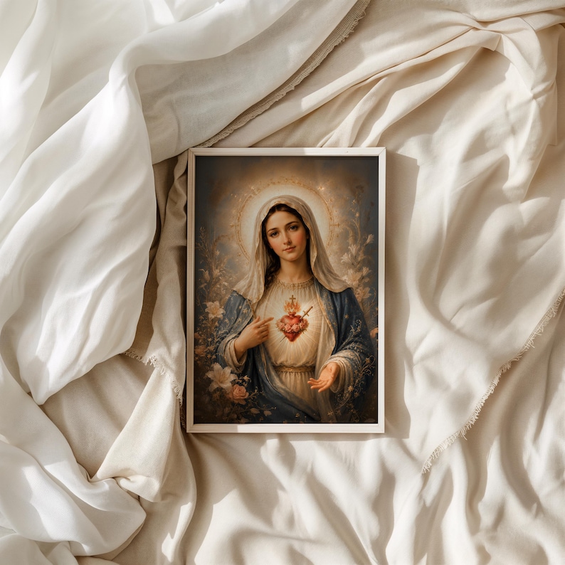May include: A rectangular framed print featuring a portrait of a woman with a veil, wearing a blue and white robe. A glowing red heart with a cross and flowers is centered on the chest. The background shows soft floral details and a golden halo.
