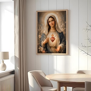 May include: A framed wall art print depicting a figure with a veil and a blue cloak, featuring a glowing, ornate heart with a small flame and a sword at the center. The figure is surrounded by soft, ethereal light and white floral elements.