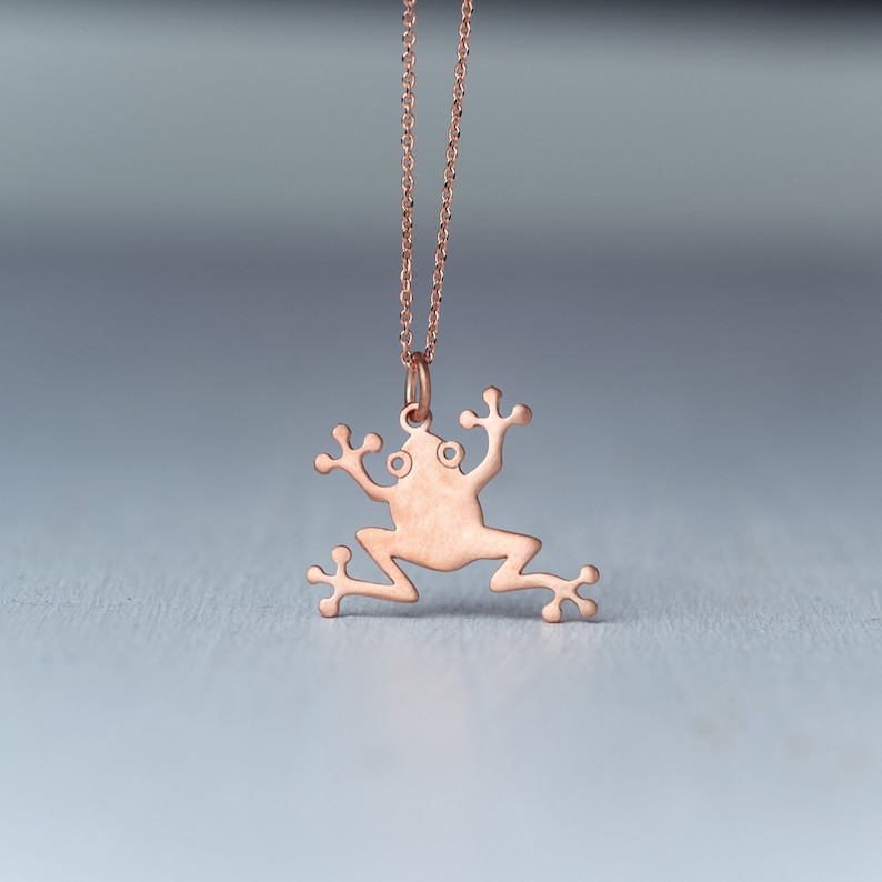May include: A rose gold necklace with a frog pendant. The frog is a simple silhouette with no details.