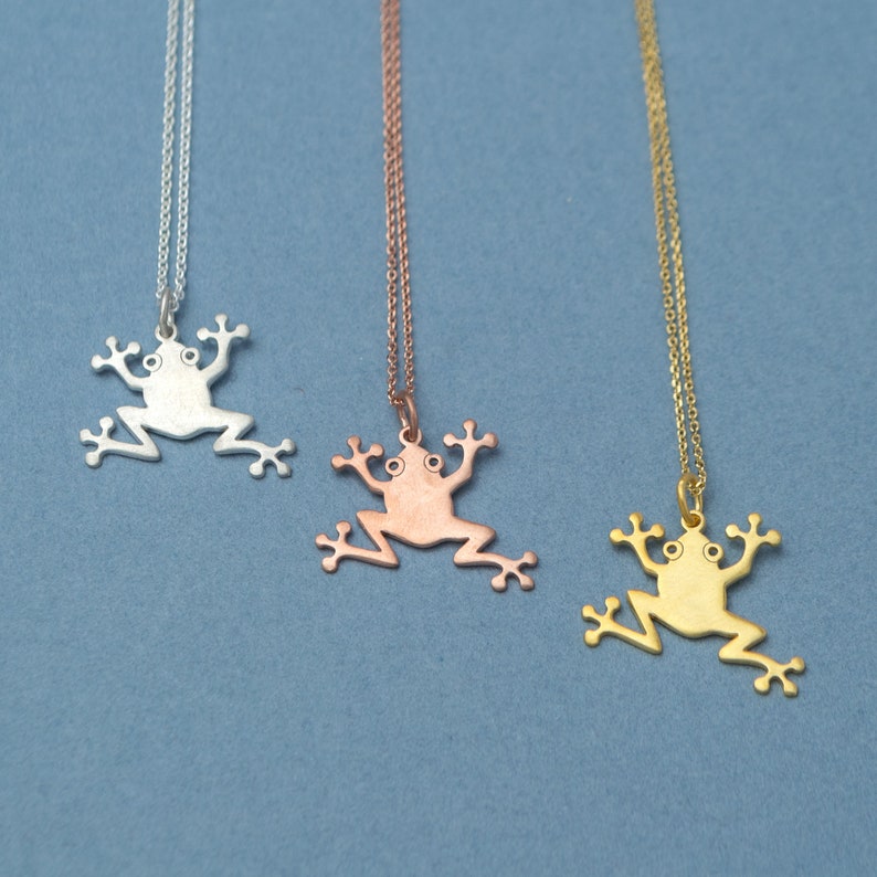 May include: Three silver, rose gold, and gold necklaces with frog pendant charms. The frog charms are all the same design, but in different metal finishes.