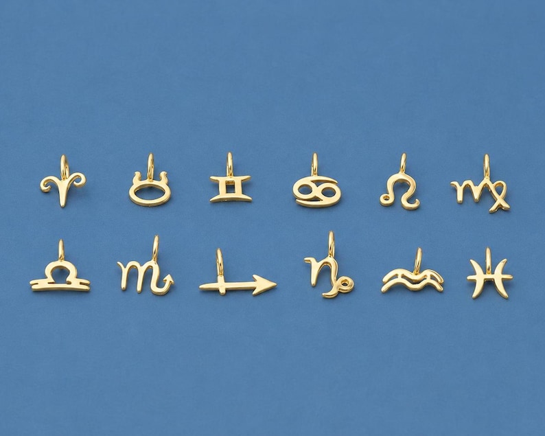 May include: Gold-colored zodiac charm pendants displayed against a blue background. Each charm represents a different astrological sign, including Aries, Taurus, Gemini, Cancer, Leo, Virgo, Libra, Scorpio, Sagittarius, Capricorn, Aquarius, and Pisces.