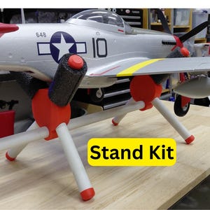 May include: A silver and red model airplane with a white star and number 10 on the side, supported by a red, white, and black stand. The text "Stand Kit" is on a yellow rectangle.