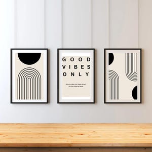 May include: Three black framed prints with white backgrounds. The center print has the text "GOOD VIBES ONLY" and the text "What makes you feel alive? Go do more of that!" The left and right prints have black and white abstract geometric designs.