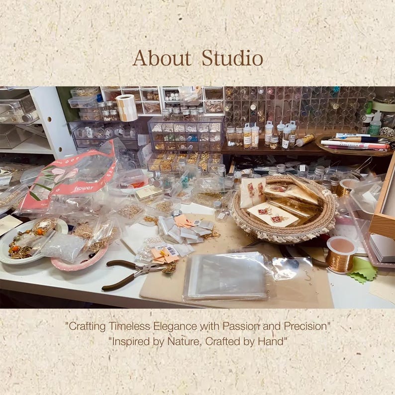 A busy jewelry workspace with various materials scattered on the table, including plastic containers filled with beads, flowers, and other jewelry-making supplies. Tools such as pliers are also visible, indicating an active crafting environment.