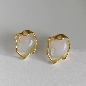 May include: A pair of gold earrings with a white, opaque, irregular shaped stone set in each earring.
