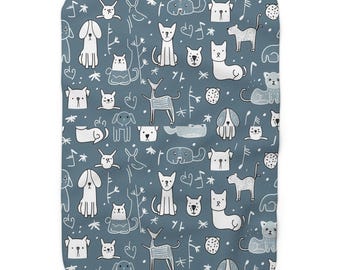 May include: A blue blanket with a repeating pattern of white line-drawn dogs, cats, deer, musical notes, and abstract shapes. The blanket has a soft, plush appearance, suitable for a child's room or pet bed.