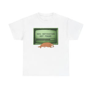May include: White t-shirt featuring a humorous graphic. The design includes a retro computer screen displaying "404: MOTIVATION NOT FOUND" above a sleeping brown dog. A fun, casual tee for everyday wear.