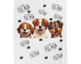 Könnte beinhalten: Weiße Decke mit drei lächelnden Cartoon-Hunden mit braunem, weißem und schwarzem Fell. Der Text "DOG MOM" ist in einem schwarzen Rahmen mit Pfotenabdrücken gedruckt.