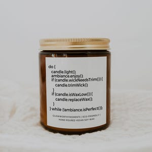 Puede incluir: Un tarro de vela de vidrio marr&oacute;n con una tapa dorada. La etiqueta dice "do { candle.light(); ambiance.enjoy(); if (candle.wickNeedsTrim()) { candle.trimWick(); } if (candle.isWaxLow()) { candle.replaceWax(); } } while (!ambiance.isPerfect()); GLOWWORTHYMOMENTS | ECO-FRIENDLY HAND POURED VEGAN SOY WAX"