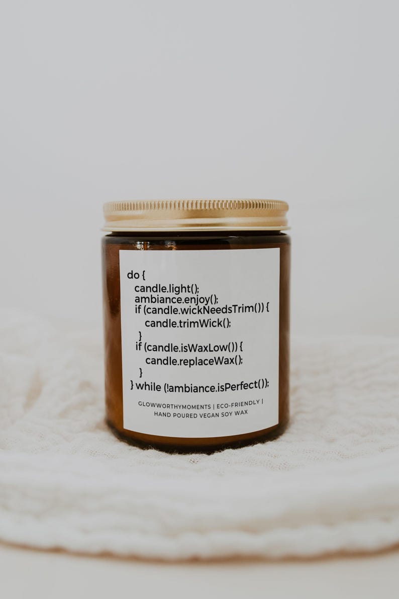 Puede incluir: Un tarro de vela de vidrio marr&oacute;n con una tapa dorada. La etiqueta dice "do { candle.light(); ambiance.enjoy(); if (candle.wickNeedsTrim()) { candle.trimWick(); } if (candle.isWaxLow()) { candle.replaceWax(); } } while (!ambiance.isPerfect()); GLOWWORTHYMOMENTS | ECO-FRIENDLY HAND POURED VEGAN SOY WAX"