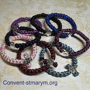 May include: A collection of colorful prayer ropes, each with a woven design and a small silver cross. The ropes are in various colors, including purple, black, blue, pink, and burgundy. The website address "Convent-stmarym.org" is visible at the bottom.