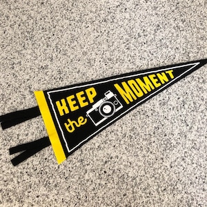 May include: Black pennant with yellow trim and white text that reads "Keep the Moment" with a camera graphic.