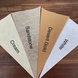 May include: Five fabric swatches in different shades of beige, cream, and white. The swatches are labeled "Cream", "Sandstone", "Desert Gold", and "White".