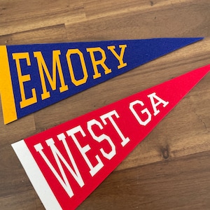 May include: Two felt pennants, one blue with yellow lettering that says "EMORY" and one red with white lettering that says "WEST GA".