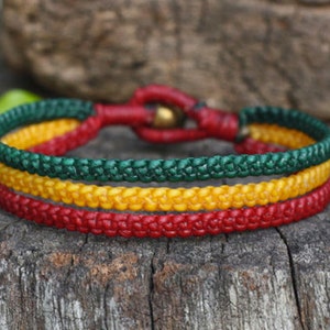 Op de afbeelding: Een gevlochten armband met drie banden van rood, geel en groen koord.