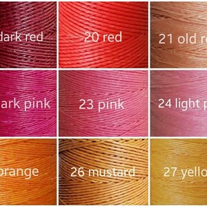 K&ouml;nnte beinhalten: Eine Farbkarte mit neun Garnspulen in verschiedenen Farbt&ouml;nen. Die Farben umfassen Dunkelrot, Rot, Altrosa, Dunkelrosa, Rosa, Hellrosa, Orange, Senf und Gelb. Jede Spule ist mit einer Nummer und einem Farbnamen beschriftet.
