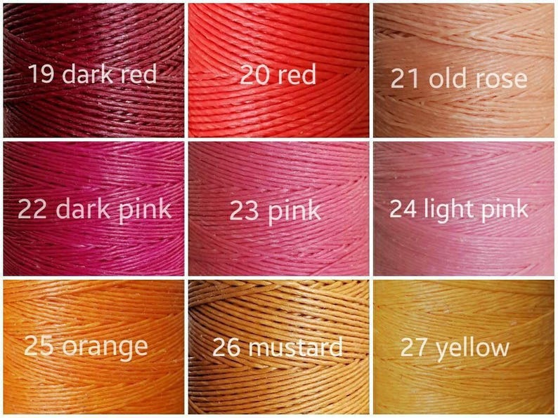K&ouml;nnte beinhalten: Eine Farbkarte mit neun Garnspulen in verschiedenen Farbt&ouml;nen. Die Farben umfassen Dunkelrot, Rot, Altrosa, Dunkelrosa, Rosa, Hellrosa, Orange, Senf und Gelb. Jede Spule ist mit einer Nummer und einem Farbnamen beschriftet.