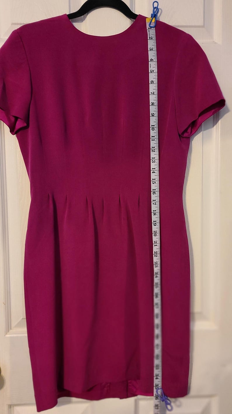 Peut inclure: Une robe magenta &agrave; manches courtes avec un col rond et une silhouette ajust&eacute;e. La robe mesure environ 94 cm de long.