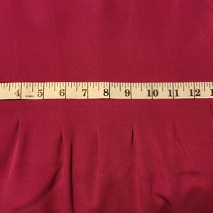 Peut inclure: Un gros plan d'une robe bordeaux avec un ruban &agrave; mesurer blanc autour de la taille. Le ruban mesure 40,6 cm.