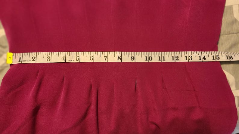 Peut inclure: Un gros plan d'une robe bordeaux avec un ruban &agrave; mesurer blanc autour de la taille. Le ruban mesure 40,6 cm.