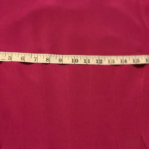Peut inclure: Un gros plan d'une robe rose fuchsia avec un m&egrave;tre ruban sur la poitrine. Le ruban indique de 1 &agrave; 20 pouces.