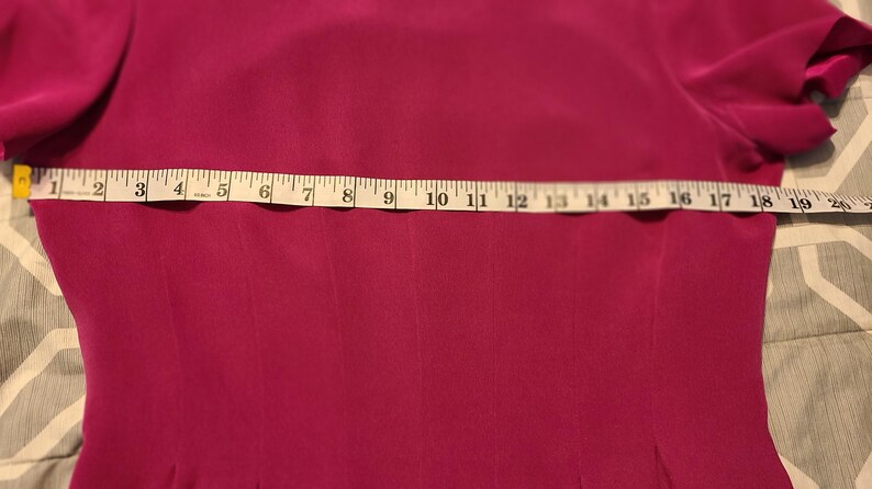 Peut inclure: Un gros plan d'une robe rose fuchsia avec un m&egrave;tre ruban sur la poitrine. Le ruban indique de 1 &agrave; 20 pouces.