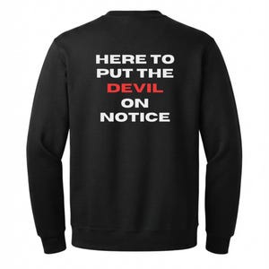 May include: A black crewneck sweatshirt featuring white text on the back that reads HERE TO PUT THE DEVIL ON NOTICE, with the word DEVIL printed in a bold red font. The garment has long sleeves and a ribbed collar, cuffs, and hemline.