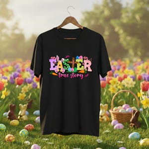 May include: Black t-shirt with the word "EASTER" in colorful letters, a bunny ear, eggs, and carrots. The phrase "true story" is below the word Easter. The shirt is hanging on a wooden hanger.