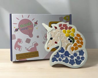 May include: A white ceramic unicorn mosaic kit with colorful tiles. The kit includes a pre-designed unicorn shape and a variety of colored tiles for creating a mosaic art piece. The box reads "Mánh Chep Tao" and "Dành cho người mới bắt đầu (Không cần cất mành)".